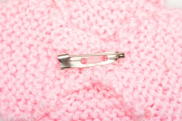 Hand knitted brooch in pink with blue pearl
